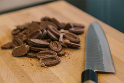 Image of Cutting board with cocoa beans cut in half and a knife on it